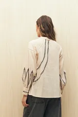 Camisa gris oscuro con estampado de triángulos blancos en el frente, mangas y cuello.