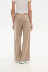 Pantalón deportivo negro de corte holgado, con cintura elástica, bolsillos laterales y botones a presión en las costuras laterales de las piernas.