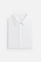 Camisa blanca de algodón, corte regular fit, cuello italiano, manga larga con puños abotonados y cierre frontal con botones.