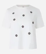 Remera de manga corta color blanco, con cuello redondo y bordados de flores en el frente.