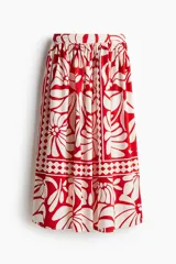 Pollera larga de popelina de algodón con estampado floral en tonos rojo y blanco. Tiene tiro alto, pretina de doble capa y cierre lateral oculto.