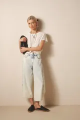 Pantalón jean de tiro medio-alto, calce holgado, relajado, con piernas anchas que se estrechan hacia el tobillo, con largo midi. Confeccionado en denim rígido con lavado bleach, que decolora el tejido hasta dejarlo casi blanco, con reservas de color en costuras y pliegues.