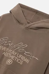 Buzo hoodie color marrón con capucha, bolsillo tipo canguro y puños y cintura acanalados. Estampado frontal con el logo de la marca y la frase "Everyday Urban Aesthetics".