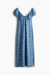 Vestido largo de lino y viscosa color celeste con estampado de flores blancas. Tiene mangas cortas abullonadas, escote corazón con tiras finas, copas preformadas con frunces, elástico en escote, hombros, mangas y cintura, cierre lateral oculto y tajo pronunciado en un lado.