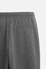 Pantalón negro de corte cropped, con cintura elástica ajustable con cordón, bolsillos laterales y traseros de vivo. El bajo tiene terminación con vuelta.