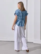 Blusa celeste estampada con motivos de playa, con cuello a la base y escote en V. Mangas cortas con detalle fruncido.