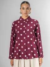 Camisa de manga larga en fibrana color bordó con estampado de lunares grandes en color crema. Presenta cuello camisero y cierre frontal de botones.