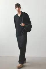 Camisa negra de tejido suave con cuello abierto, tapeta lisa y canesú en la espalda. Modelo de manga larga con cierre ajustable de botones en los puños y tapeta con botón. Bajo recto y corte estándar.