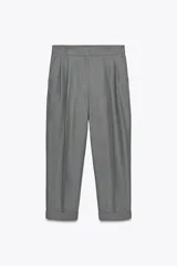 Pantalón gris de corte cropped, tiro alto, con bolsillos delanteros, cintura elástica en la parte trasera y cierre frontal con cremallera y botones.