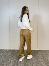 Pantalón babucha cargo color beige, de corte holgado, con cintura elástica, bolsillos laterales y tobillos ajustados.