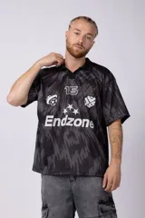 Camiseta de fútbol negra con estampado abstracto en gris, cuello tipo chomba y logos estampados en el frente.