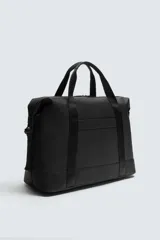 Bolso de viaje negro con acabado texturizado, compartimento principal con cierre de cremallera, bolsillo plano trasero con cierre de cremallera, banda de sujeción para equipaje y asa de hombro removible y ajustable.