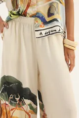Pantalón palazzo de seda color crema con estampado de paisaje.