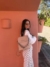 Mochila color verde oliva, tipo cartera, con tapa y doble cierre. Tiene dos compartimentos y división interna, además de un bolsillo trasero con cierre.