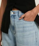 Pantalón de jean wide leg de tiro alto, color azul oscuro, con bolsillos delanteros y traseros, trabillas para cinturón y cierre frontal con cremallera y botón.