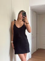 Vestido corto tejido en algodón y lurex color verde militar, con escote en la espalda y tiras con borlas que regulan el largo.