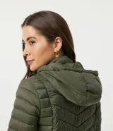 Campera puffer larga color verde militar, confeccionada en poliamida con relleno de poliéster. Tiene capucha ajustable, cierre frontal con cremallera, cuello alto y bolsillos laterales.