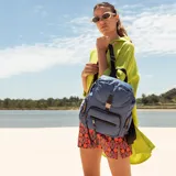 Mochila azul de nylon con tapa y broche metálico. Tiene apertura superior con broche, bolsillos internos, bolsillo con cierre metálico al frente y laterales, asas rígidas de mano y correas regulables para colgar en la espalda.