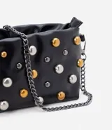Bolso bandolera pequeño color negro, con correa de cadena desmontable y tachas redondas plateadas y doradas.