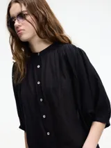 Camisa negra de algodón con cuello mao y botones frontales. Tiene mangas 3/4 amplias y un corte recto.