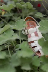 Sandalias de cuero marrón con tiras entrecruzadas y hebilla dorada al tobillo.