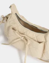 Bandolera color crema de tela deportiva acolchada con diseño de rombos. Tiene manija de cadena metálica, cierre superior, bolsillo frontal con lazo y bolsillos laterales con lazo.