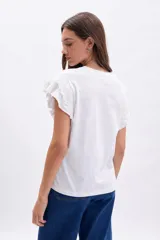 Remera de manga corta color blanco, con detalle de volados en broderie en las mangas y cuello redondo.