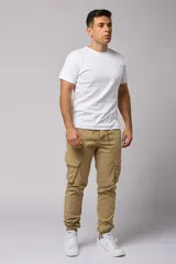 Pantalón cargo color beige de gabardina, con corte ajustado, bolsillos laterales con fuelle y puños elásticos en los tobillos.