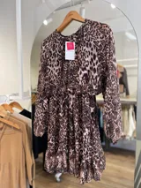 Vestido corto con estampado animal print, de mangas largas traslúcidas y falda con volados.