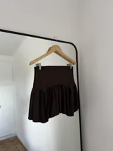 Shorts o minifalda color marrón oscuro, con diseño de volados en el ruedo y cintura alta.