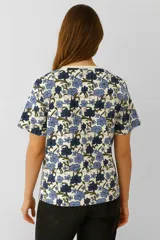 Remera de manga corta color marrón con estampado de flores en tonos beige y marrón oscuro, corte holgado y cuello redondo.