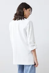 Blazer color crudo de corte recto, con cuello solapa, mangas 3/4 con botón y bolsillos frontales.