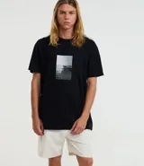 Remera negra de mangas cortas, confeccionada en media malla de algodón con cuello redondo y estampa photoprint de playa. Modelo cómodo de corte holgado.