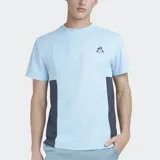 Remera deportiva Le Coq Sportif de manga corta, color celeste claro con paneles laterales en azul oscuro. Presenta cuello redondo y el logo del gallo en el pecho.