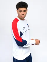Buzo de felpa azul marino, con mangas largas, cuello redondo y puños acanalados. Presenta cortes en blanco y rojo en la parte superior, logo de Umbro bordado en el pecho y escudo del Club Nacional de Football.