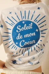 Remera blanca de algodón con estampado en la espalda de un sol azul con la frase "Soleil de mon Coeur".