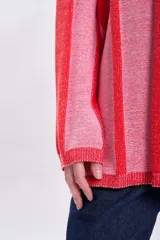 Sweater de punto tejido a rayas verticales rosas y rojas, de corte holgado y cuello redondo.