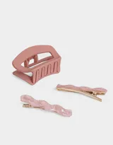 Set de accesorios para el pelo que incluye un broche rectangular y dos hebillas onduladas, todos de resina color rosa.