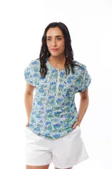 Blusa estampada con flores azules y verdes, de manga corta con cierre metálico en el frente.