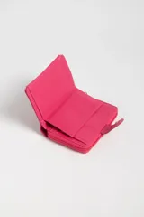 Billetera pequeña fucsia con textura símil cocodrilo, cierre con broche a presión y compartimento con cierre de cremallera.