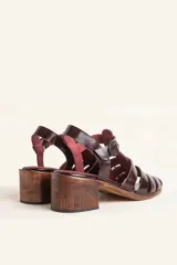 Sandalias de cuero color borgoña con tiras entrecruzadas, hebilla lateral y taco de madera.