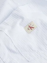 Camisa cropped de popelina de algodón suave a rayas verticales celestes y blancas, de corte relaxed, con cuello en punta, puños segados, bajo redondeado y bolsillo en el pecho con insignia con el logo de Calvin Klein.