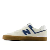 Championes New Balance modelo NM574 VRU, color beige con detalles en azul y blanco, suela de goma marrón y logo "N" en los laterales.