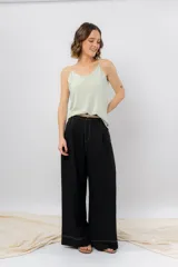 Pantalón negro de corte ancho y fluido, tiro medio con presillas para cinturón, bolsillos laterales funcionales y pinzas delanteras.