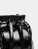 Mochila negra de cuerina acolchada con diseño de líneas diagonales. Tiene solapa con broche decorativo y botón para cerrar. Cuenta con correas regulables, manija superior de material principal y metal, y tira de ajuste de metal.
