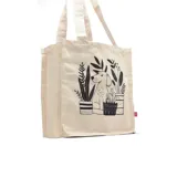 Bolso tipo tote bag color crudo con asas de tela y estampado de un perro y plantas en macetas.