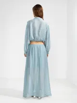 Blusa corta celeste de tejido arrugado liviano, con cuello mao, botones al frente, mangas abullonadas y ruedo elastizado.