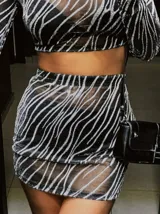Conjunto de top manga larga y minifalda con estampado de líneas brillantes sobre tela transparente negra.