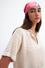 Remera color crudo de tejido calado con cuello polo y mangas cortas.