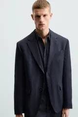 Blazer azul marino de lino con corte regular fit, cuello con solapas de muesca, manga larga con puños abotonados, bolsillo de vivo en el pecho, bolsillos de solapa en la cadera, bolsillo interior, aberturas en la espalda y cierre frontal de botonadura.